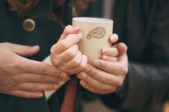 Coppia il riscaldamento delle sue mani su una tazza di tè caldo fotografia stock Coppia il riscaldamento delle sue mani su una tazza di tè caldo fotografia stock
