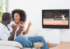 Coppia incoraggiare mentre guardano la partita del tennis sulla televisione fotografia stock Coppia incoraggiare mentre guardano la partita del tennis sulla televisione fotografia stock