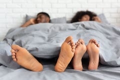 Coppie afroamericane che dormono a piedi nudi a letto fotografia stock Coppie afroamericane che dormono a piedi nudi a letto fotografia stock