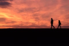 Coppie che camminano giù un tramonto molto arancio immagine stock libera da diritti Coppie che camminano giù un tramonto molto arancio immagine stock libera da diritti