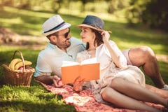 Coppie che godono del libro di lettura all'aperto di tempo di picnic fotografia stock libera da diritti Coppie che godono del libro di lettura all'aperto di tempo di picnic fotografia stock libera da diritti