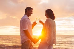 Coppie che godono del vetro di Champene sulla spiaggia al tramonto fotografia stock libera da diritti Coppie che godono del vetro di Champene sulla spiaggia al tramonto fotografia stock libera da diritti