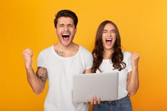 Coppie con il computer portatile che grida e pugni di serraggio come i vincitori fotografie stock libere da diritti Coppie con il computer portatile che grida e pugni di serraggio come i vincitori fotografie stock libere da diritti