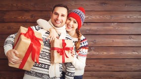 Coppie felici della famiglia con i regali di Natale i su fondo di legno fotografia stock Coppie felici della famiglia con i regali di Natale i su fondo di legno fotografia stock