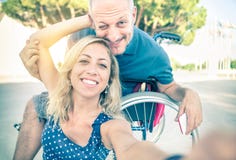 Coppie felici nell'amore che prende selfie con la sedia a rotelle immagine stock Coppie felici nell'amore che prende selfie con la sedia a rotelle immagine stock