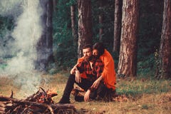 Coppie nell'amore al picnic con fuoco in foresta, alberi fotografie stock Coppie nell'amore al picnic con fuoco in foresta, alberi fotografie stock