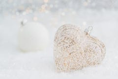 Cora??o de vidro em uma neve Fundo branco borrado do bokeh de brilho com luzes de incandesc?ncia Decora??o do Natal Copie o espa? fotografia de stock Cora??o de vidro em uma neve Fundo branco borrado do bokeh de brilho com luzes de incandesc?ncia Decora??o do Natal Copie o espa? fotografia de stock