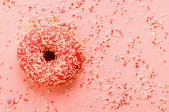 Coral donut lying on pink. Donut decorated with icing on pink stock photos Coral donut lying on pink. Donut decorated with icing on pink stock photos