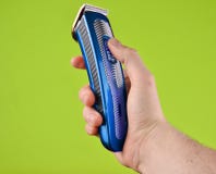 Cordless clipper in a male hand isolated on a green background. stock photo Cordless clipper in a male hand isolated on a green background. stock photo