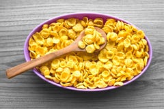 Cornflakes i en purpurfärgad bunke på en grå bakgrund royaltyfri foto Cornflakes i en purpurfärgad bunke på en grå bakgrund royaltyfri foto
