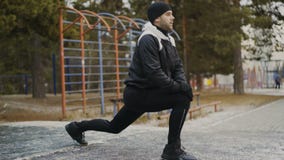 Corredor atractivo del hombre que hace estirando el ejercicio que se prepara para el entrenamiento de la mañana y que activa en p metrajes Corredor atractivo del hombre que hace estirando el ejercicio que se prepara para el entrenamiento de la mañana y que activa en p metrajes
