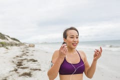 Corridore femminile che prepara per l'allenamento all'aperto sulle cuffie di messa in opera della spiaggia Immagini Stock Libere da Diritti Corridore femminile che prepara per l'allenamento all'aperto sulle cuffie di messa in opera della spiaggia Immagini Stock Libere da Diritti