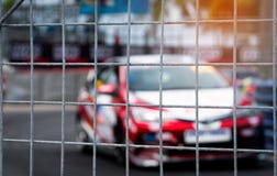 Corsa di automobile del Motorsport sulla strada asfaltata Vista dal reticolato della maglia del recinto sull'automobile vaga sul immagini stock Corsa di automobile del Motorsport sulla strada asfaltata Vista dal reticolato della maglia del recinto sull'automobile vaga sul immagini stock