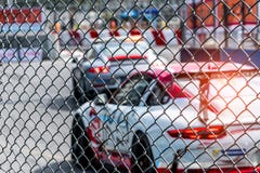 Corsa di automobile del Motorsport sulla strada asfaltata Vista dal reticolato della maglia del recinto sull'automobile vaga sul immagini stock Corsa di automobile del Motorsport sulla strada asfaltata Vista dal reticolato della maglia del recinto sull'automobile vaga sul immagini stock