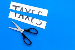 Corte o conceito dos impostos Sciccors cortou o papel com impostos da palavra no espaço azul da cópia da opinião superior do fund imagem de stock Corte o conceito dos impostos Sciccors cortou o papel com impostos da palavra no espaço azul da cópia da opinião superior do fund imagem de stock