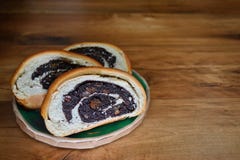 Cortou o pão fresco corado com as sementes de papoila que encontram-se em uma placa redonda da argila em uma superfície de madeir imagem de stock Cortou o pão fresco corado com as sementes de papoila que encontram-se em uma placa redonda da argila em uma superfície de madeir imagem de stock