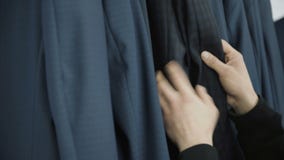 Cose omhoog van de knappe mens die een kostuum in de rij in de winkel kiezen 4K stock footage Cose omhoog van de knappe mens die een kostuum in de rij in de winkel kiezen 4K stock footage