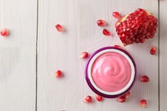 Cosmetic cream in a lilac jar and with fresh pomegranate on a white wooden table. pomegranate extract. cosmetics stock photo Cosmetic cream in a lilac jar and with fresh pomegranate on a white wooden table. pomegranate extract. cosmetics stock photo