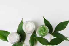 Cosmetici naturali crema, sale marino con le foglie per il fondo bianco della tavola della stazione termale casalinga del bagno p immagine stock Cosmetici naturali crema, sale marino con le foglie per il fondo bianco della tavola della stazione termale casalinga del bagno p immagine stock