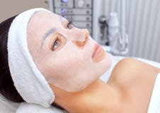 Cosmetologist для процедуры очищать и moisturizing кожу, прикладывая маску листа к стороне стоковое изображение Cosmetologist для процедуры очищать и moisturizing кожу, прикладывая маску листа к стороне стоковое изображение