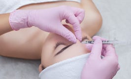 Cosmetologist доктора делает Rejuvenating лицевую процедуру по впрысок для затягивать и приглаживать морщинки на коже стороны Стоковые Изображения RF Cosmetologist доктора делает Rejuvenating лицевую процедуру по впрысок для затягивать и приглаживать морщинки на коже стороны Стоковые Изображения RF
