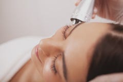 Cosmetologist прекрасной молодой женщины посещая на клинике красоты стоковое изображение Cosmetologist прекрасной молодой женщины посещая на клинике красоты стоковое изображение