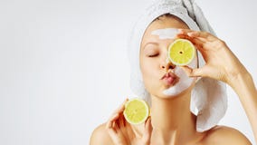Cosmetology, skin care, face treatment, spa and natural beauty concept. Woman with facial mask holds lemons