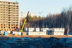 Costruzione di nuovo edificio multipiano circondato dalle foreste Gru di costruzione contro il cielo blu fotografia stock Costruzione di nuovo edificio multipiano circondato dalle foreste Gru di costruzione contro il cielo blu fotografia stock
