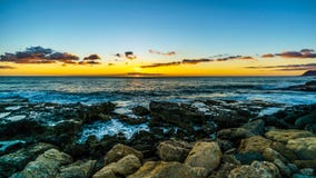 Coucher du soleil au-dessus de l'horizon avec quelques nuages et les rivages rocheux de la côte ouest d'Oahu photographie stock libre de droits Coucher du soleil au-dessus de l'horizon avec quelques nuages et les rivages rocheux de la côte ouest d'Oahu photographie stock libre de droits