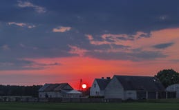 Coucher du soleil rouge derrière de vieux bâtiments de ferme image stock Coucher du soleil rouge derrière de vieux bâtiments de ferme image stock