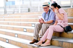 Couple of Asian old man and woman tourist are looking at tablet and acting like get some good news. This photo also contain stock photos Couple of Asian old man and woman tourist are looking at tablet and acting like get some good news. This photo also contain stock photos
