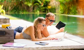 Couple with computers relaxing in sofa by the pool Royalty Free Stock Photos Couple with computers relaxing in sofa by the pool Royalty Free Stock Photos