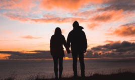 A couple holding hands at sunset by the sea stock photos A couple holding hands at sunset by the sea stock photos