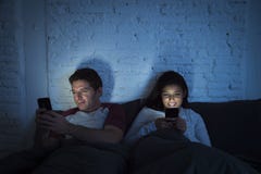 Couple at home in bed late at night using mobile phone in relationship communication problem Royalty Free Stock Images Couple at home in bed late at night using mobile phone in relationship communication problem Royalty Free Stock Images
