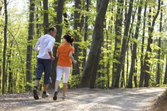 Couple jogging in forest, view from behind.