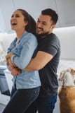 Couple laughing in the kitchen while he is holding her stock photography Couple laughing in the kitchen while he is holding her stock photography