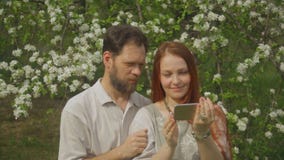 A couple in love looks at photos on the smartphone screen and takes a selfie. stock footage A couple in love looks at photos on the smartphone screen and takes a selfie. stock footage