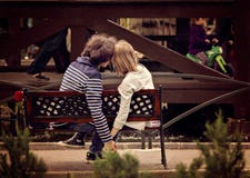 Young couple holding hands on bench in park.