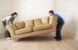 Couple Placing Sofa In Living Room Of New Home