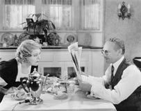 Couple reading newspaper at breakfast table stock images Couple reading newspaper at breakfast table stock images