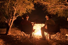 Couple sitting at burning camp fire in the night. Camping in the forest under starry sky, Namibia, Africa. Summer adventures and e royalty free stock images Couple sitting at burning camp fire in the night. Camping in the forest under starry sky, Namibia, Africa. Summer adventures and e royalty free stock images