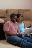 Couple Sitting In Front Of Couch With Laptop Com Stock Photo