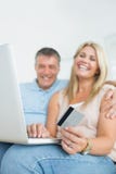Couple sitting on sofa shopping online Royalty Free Stock Photography Couple sitting on sofa shopping online Royalty Free Stock Photography