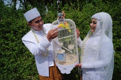 A couple smiling happily while watching a beautiful bird in a cage