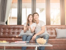 Couple on sofa with TV remote watching television in living room royalty free stock image Couple on sofa with TV remote watching television in living room royalty free stock image