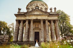 Couple stands among the field flowers before old chapel stock image Couple stands among the field flowers before old chapel stock image