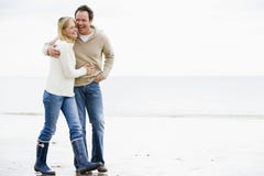 Couple walking on beach arm in arm smiling stock photo Couple walking on beach arm in arm smiling stock photo