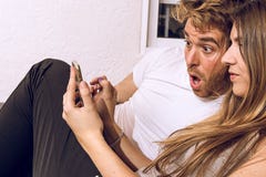 Couple With A Surprised Face Looking At The Mobile Phone Royalty Free Stock Photo