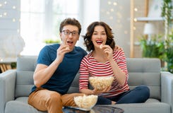 Couple With Popcorn Sitting On Sofa Royalty Free Stock Photography