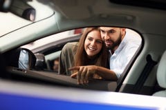 Couples adultes choisissant la nouvelle voiture dans la salle d'exposition photo stock Couples adultes choisissant la nouvelle voiture dans la salle d'exposition photo stock